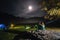 Night camping. Romantic couple tourists have a rest near illuminated tent under amazing night sky with moon. mist creeps over the