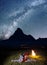 Night camping. Romantic lovers lying near the fire and enjoying incredibly beautiful starry sky. Long exposure