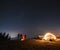 Night campsite in the mountains lawn under starry sky.
