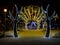 Night city Christmas decoration light arch with golden yellow new year garland and trees on the central square of the