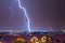 Night city panorama with lightning strike