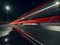 Night city scene with puddle by a road and car light trail. Dark night sky. Town traffic