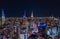 Night city scene of tall downtown skyscrapers in metropolis. High rise buildings with colour illuminated spires on tops