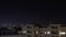 Night city timelapse. Stars and new moon move on the sky. Residential flats windows lights up and turns off. City skyline