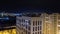 Night city timelapse. Wide angle panorama with residental high-rise and small buildings. Traffic blurred lights on road