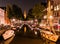 Night city view of Amsterdam. Boats in a channel and typical dutch houses, Holland, Netherlands.