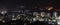 Night city view with light trails on distant road and burning glass on other side