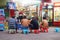 At night, farmers construction workers watch TV in front of a small shop.