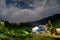 Night fisheye shot of a hill station lit by the light from buildings, a cloudy star studded sky and trees in McLeodganj