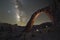 Night hiker standing under Corona Arch with the Milky Way Galaxy