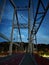 Night iron bridge in perspective. On the background of a dark blue sky with clouds and a forest