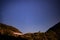 Night landscape with an alpine refuge and starry sky seen from rocky mountains