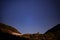 Night landscape with an alpine refuge and starry sky seen from rocky mountains