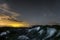 Night landscape with chalk ridges under cloudy and starry sky.