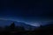 Night landscape with dark sky and stars in Slovenia, nature in Europe. Foggy Triglav Alps with forest, travel in Slovenia.