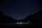 Night landscape, illuminated alpine lodge, mountain silhouette and starry sky