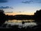 Night landscape on the water with bushes and trees with small clouds on the sky.