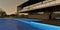 Night lighting of the pool on the roof of a country cottage. The steps are translucent under the blue water. Decking all around.