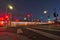 Night lights of a commuter train streak across a street intersection next to a crosswalk.