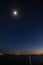 Night long exposure of the sky with the bright moon and stars over the sea