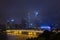 Night modern city with skyscrapers. Bridge over the river, city buildings glow at night. The sky in the clouds hides the building.