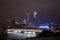 Night modern city with skyscrapers. Bridge over the river, city buildings glow at night. The sky in the clouds hides the building.