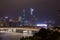 Night modern city with skyscrapers. Bridge over the river, city buildings glow at night. The sky in the clouds hides the building.