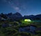 Night mountain landscape with illuminated tent.