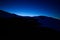Night mountains landscape view with dark deep blue sky stars and sunset dusk evening lightning on the horizon, black hills and one