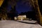 Night photo of the winter view of a cozy little house strewn with snow and festive lights.