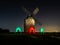 Night photograph of a windmill with the silhouette of don Xijote