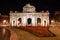 Night photography of the eastern faÃ§ade of Puerta de AlcalÃ¡ and a red garden