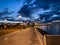 night promenade at pier blue dramatic sky street lamp light blurred at sea water