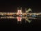 The night scene of brightly light up Shah Mosque and arcade shop bazaar with reflection in pool at Naqah-e Jahan Square.