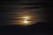 Night scene - full moon shining brightly in sky with clouds on mountains background.