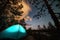 Night scene with illuminated camping tent, forest, starry sky and illuminated clouds