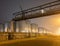 Night scene with large silo and pipeline overpass at petrochemical production plant