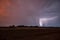 Night scenery of a thunderstorm, with orange illumination of clouds because of a steppe fire