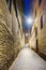 Night shot of a lonely and narrow cobblestone alley with facades of stone houses