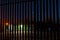 Night shot of a small road maintenance yard. Dark blue sky with stars. Metal fence in foreground