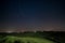 Night sky in the cultivated hill range and cereal crop fields illuminated by moon light. Stars over rural villages of Tuscany,