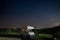 Night sky in the cultivated hill range and cereal crop fields of Tuscany, Italy. Stars over camper van illuminated by moon light.