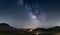Night sky over Castelluccio di Norcia highlands, Italy. The Milky Way galaxy core and stars over illuminated village unique hills
