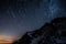 Night sky star trails above Aiguille de Bionnassay mountain, Alps, France