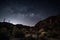 night sky with stars and moon over desert canyon, silhouetting the cliffs