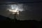 Night thunderstorm, distant illuminated cumulonimbus cloud and cloudy sky, power lines, power pole