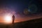 A night time stars edit of a silhouette of a lone man with a rucksack walking towards a light in the nights sky on a hill