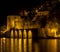 Night view of ancient stone ship port, castle, walls with lights reflected to the sea and behind it old city houses Alanya Antalya