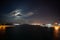 Night view of Athens Piraeus harbor with moon partially hidden by clouds