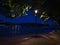 Night view of flooded promenade on Rhine riverside with high water level and lantern light below tree in town Koblenz.